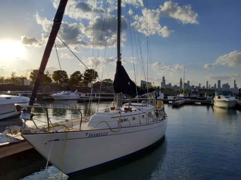 Slide: The Image of 1969 Chris-Craft Apache 37 sailboat docked at sunset with city skyline in background. - 2
