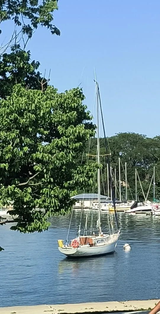 Slide: The Image of 1969 Chris-Craft Apache 37 sailboat moored on a calm lake, surrounded by trees. - 3