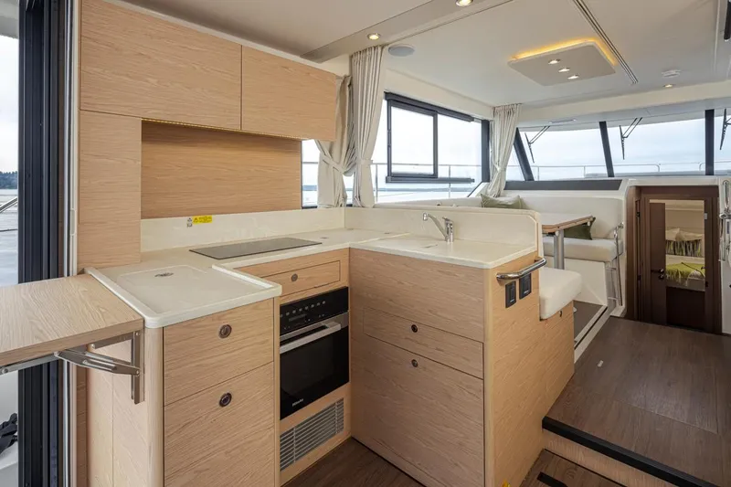 Slide: The Image of Modern kitchen interior of 2026 Beneteau Swift Trawler 41 Fly, featuring sleek wood cabinetry and appliances. - 12
