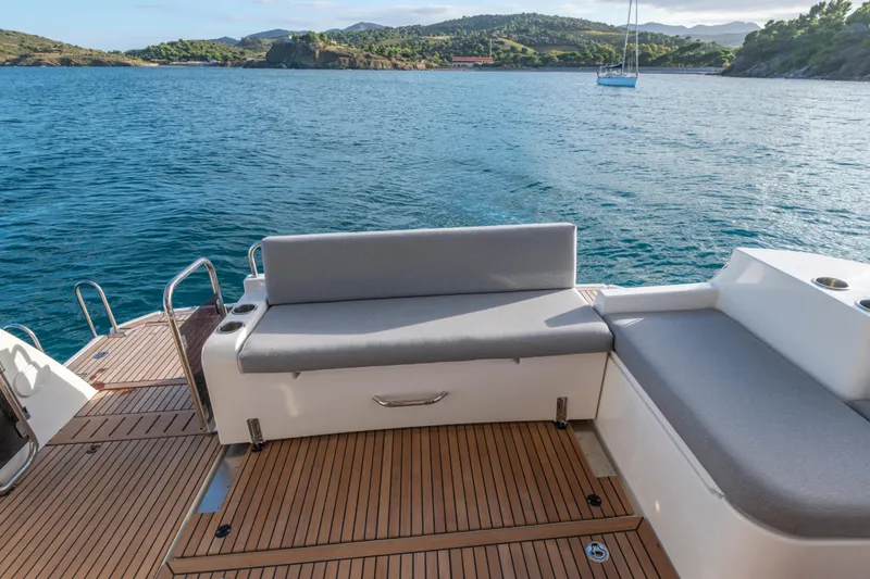 Slide: The Image of 2026 Beneteau Swift Trawler 41 Fly deck with seating, overlooking serene waters and distant hills. - 15
