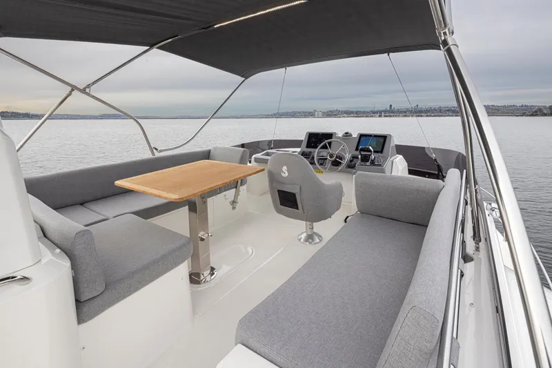 Slide: The Image of 2026 Beneteau Swift Trawler 41 Flybridge with seating, table, and helm on calm water. - 19