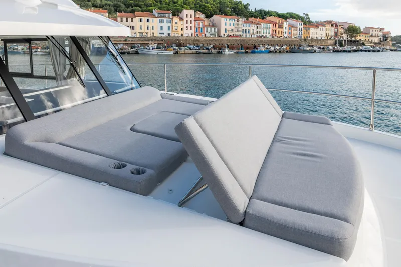 Slide: The Image of 2026 Beneteau Swift Trawler 41 Fly with adjustable sun loungers, docked near colorful waterfront buildings. - 3