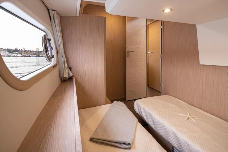 Slide: The Image of Interior of 2026 Beneteau Swift Trawler 41 Fly cabin with twin beds and window view. - 34