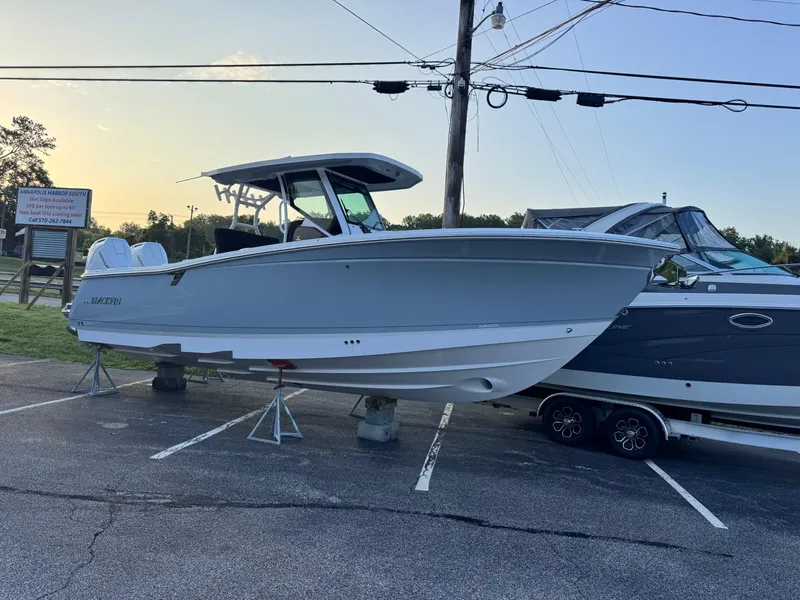The Image of 2025 Blackfin 302 CC boat displayed on stands in a parking lot. - 0