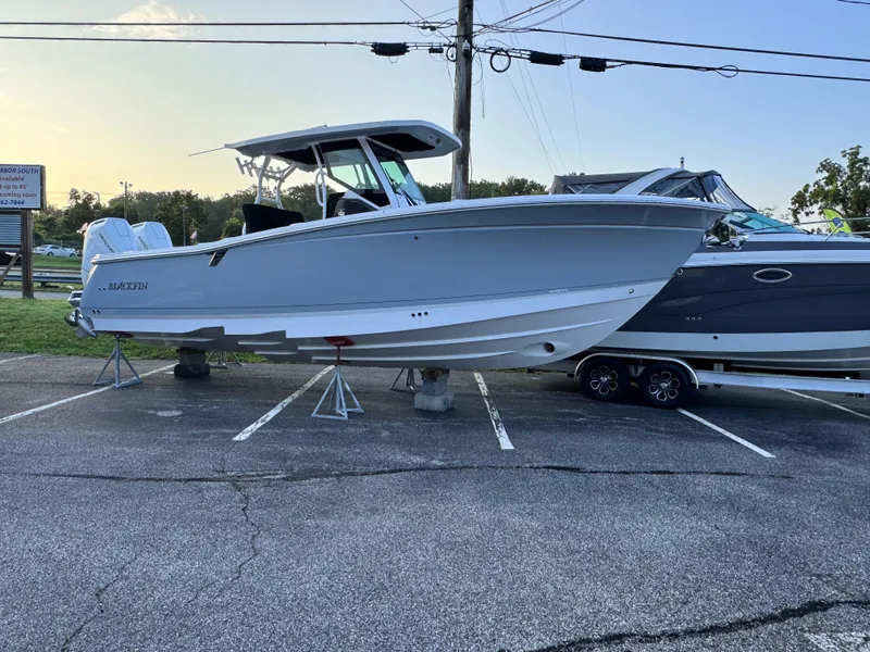 Slide: The Image of 2025 Blackfin 302 CC boat displayed on stands in a parking lot. - 2