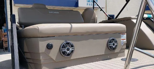Slide: The Image of 2024 Sylvan Mirage 8520 CLZ DH pontoon boat with beige seating and built-in speakers. - 2