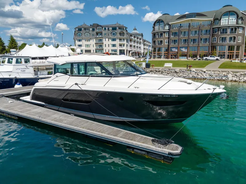 The Image of 2022 Tiara Yachts C49 Coupe docked in a marina with luxury buildings in the background. - 0