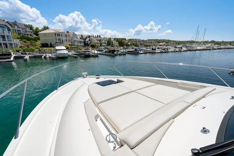 Slide: The Image of 2022 Tiara Yachts C49 Coupe on serene waterfront with luxury homes and marina. - 12