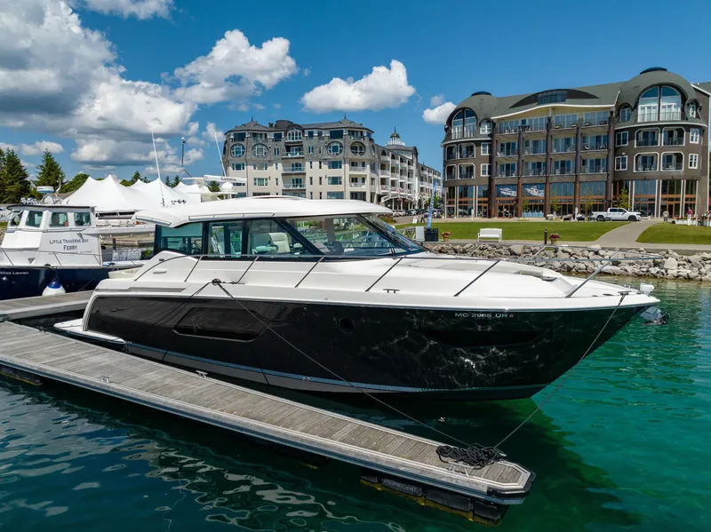 Slide: The Image of 2022 Tiara Yachts C49 Coupe docked at a marina with luxury buildings in the background. - 2