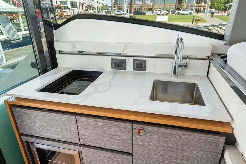 Slide: The Image of 2022 Tiara Yachts C49 Coupe kitchen area with sink and stovetop, modern design. - 29