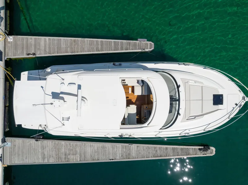 Slide: The Image of 2022 Tiara Yachts C49 Coupe docked, aerial view, clear green water. - 4