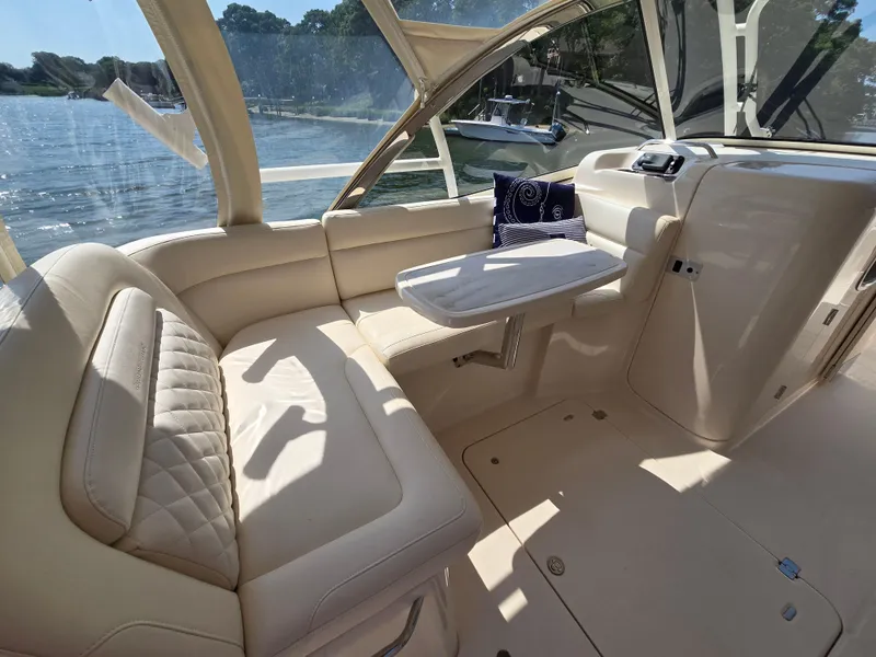 Slide: The Image of 2017 Grady-White Freedom 335 boat interior with beige seating and table, overlooking water. - 11