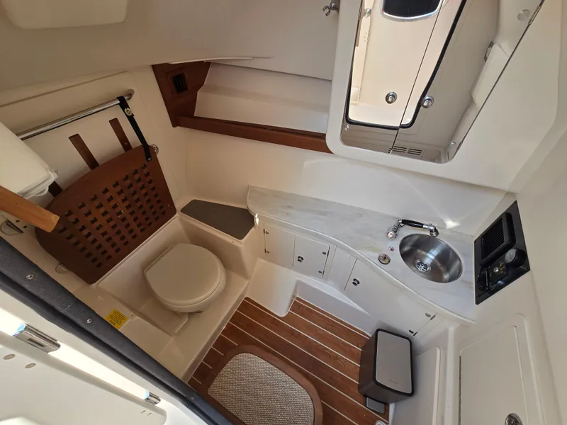 Slide: The Image of 2017 Grady-White Freedom 335 boat interior with toilet, sink, and wooden accents. - 16