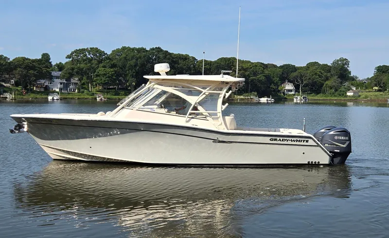 Slide: The Image of 2017 Grady-White Freedom 335 boat on calm water, surrounded by trees and houses. - 3