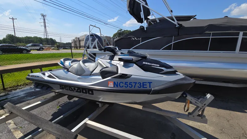 Slide: The Image of 2021 Sea-Doo GTX Limited 300 jet ski on trailer, parked near a boat. - 2