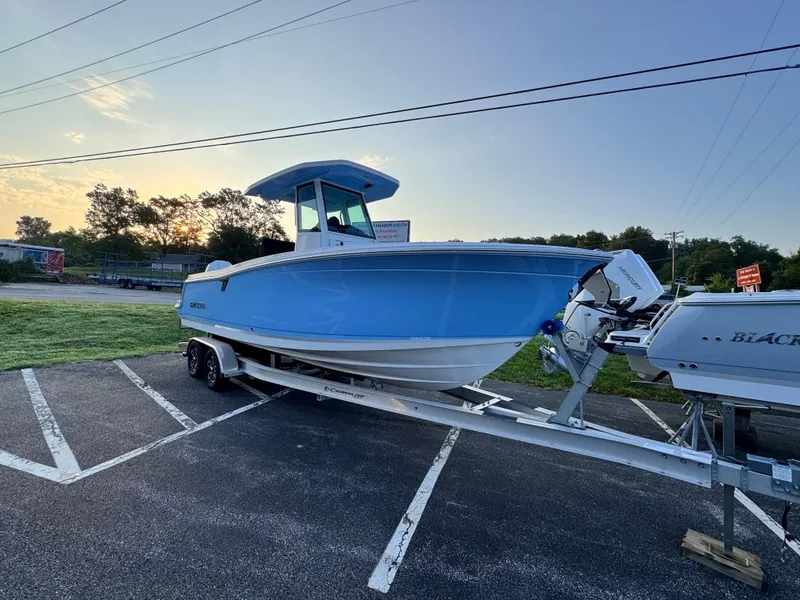 Slide: The Image of 2025 Blackfin 252 CC boat on trailer at sunset, parked in a lot. - 0