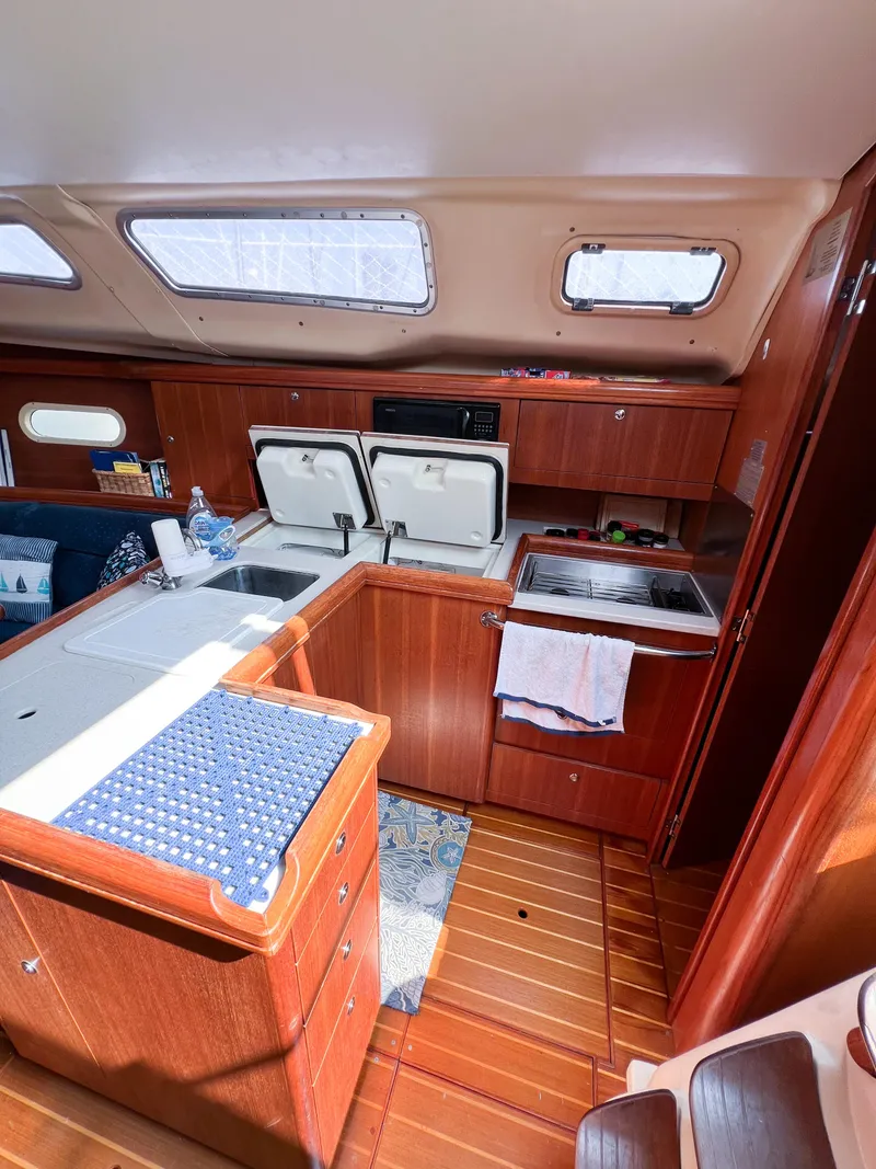 Slide: The Image of 2002 Hunter 356 yacht interior with wooden cabinetry, kitchen area, and natural light. - 15