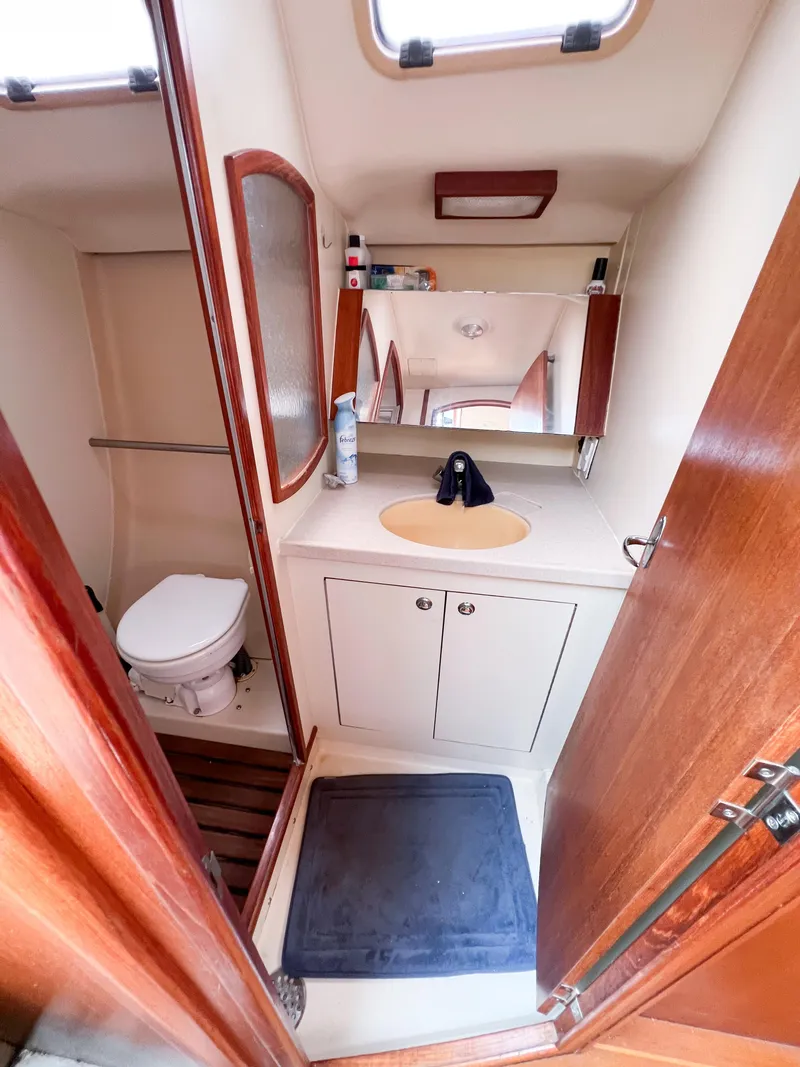Slide: The Image of Compact bathroom in a 2002 Hunter 356 sailboat, featuring a sink, toilet, and mirror. - 18