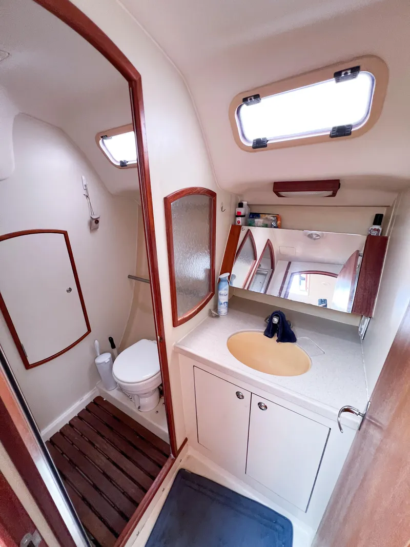Slide: The Image of Compact bathroom in a 2002 Hunter 356 sailboat, featuring a toilet, sink, and storage cabinets. - 19