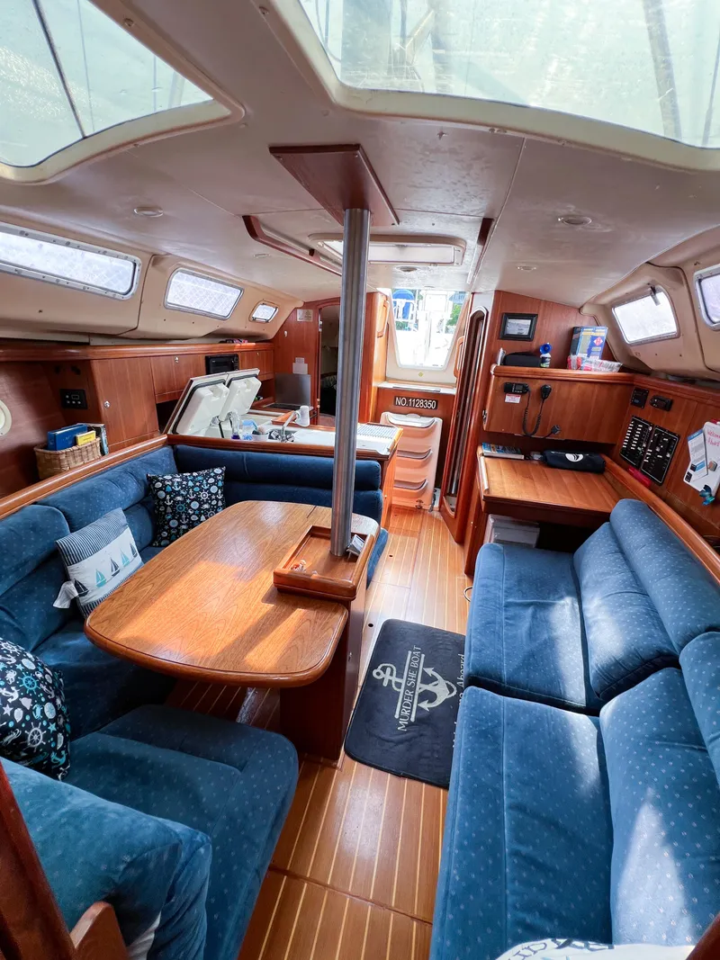 Slide: The Image of Interior of 2002 Hunter 356 sailboat with blue seating and wooden table. - 30