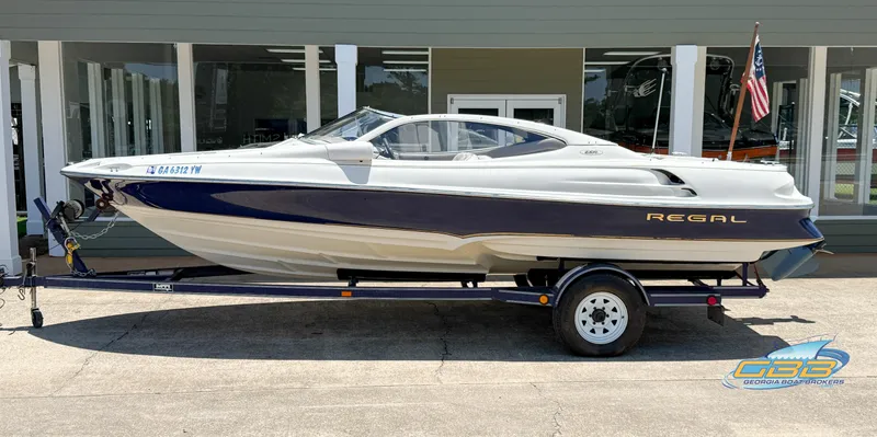The Image of 1998 Regal 2100 LSR boat on trailer, parked outside dealership. - 1