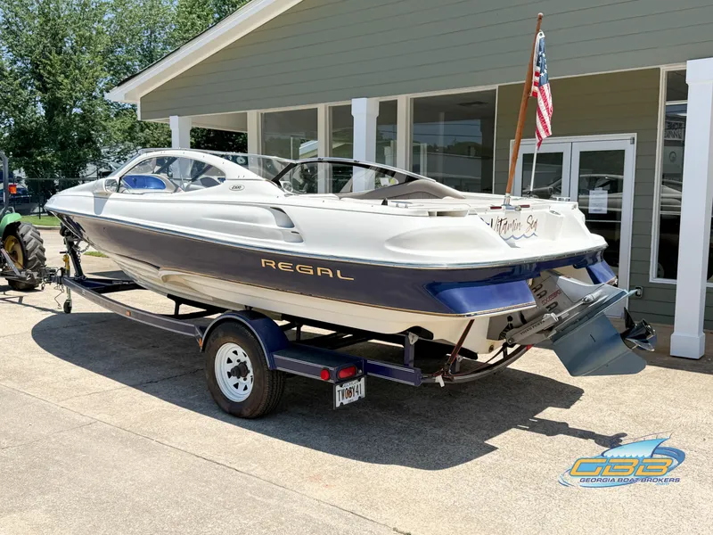 Slide: The Image of 1998 Regal 2100 LSR boat on trailer, parked outside a building. - 6