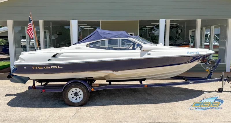 Slide: The Image of 1998 Regal 2100 LSR boat on trailer, displayed outdoors with American flag. - 8