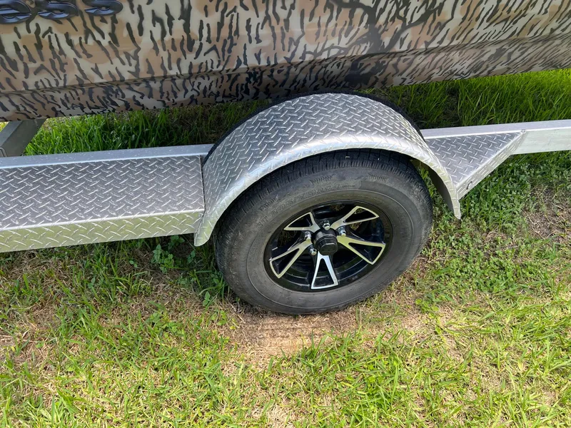 Slide: The Image of Trailer wheel of 2022 Xpress H190B boat on grass, featuring camouflage design. - 7