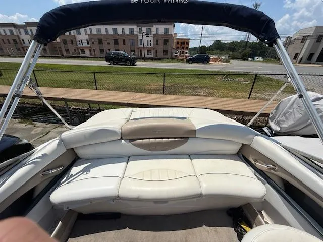 Slide: The Image of 2005 Four Winns 190 Horizon boat interior with white seating and canopy, parked near a road. - 7