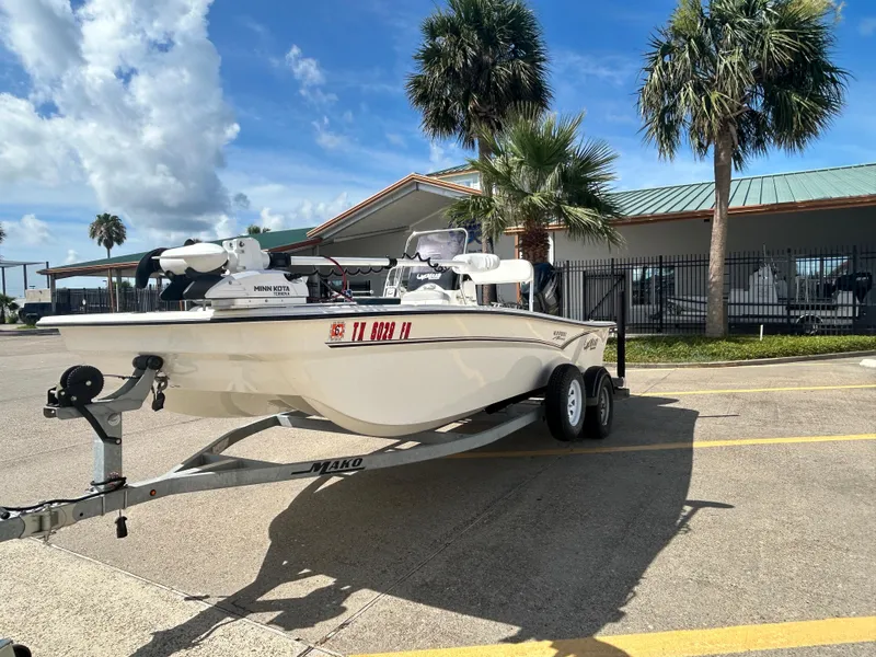 Slide: The Image of 2020 Mako Pro Skiff 17 CC boat on trailer, parked near palm trees and building. - 3