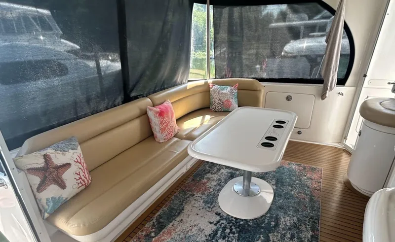 Slide: The Image of 2002 Sea Ray 480 Motor Yacht interior with beige seating, decorative pillows, and a central table. - 11