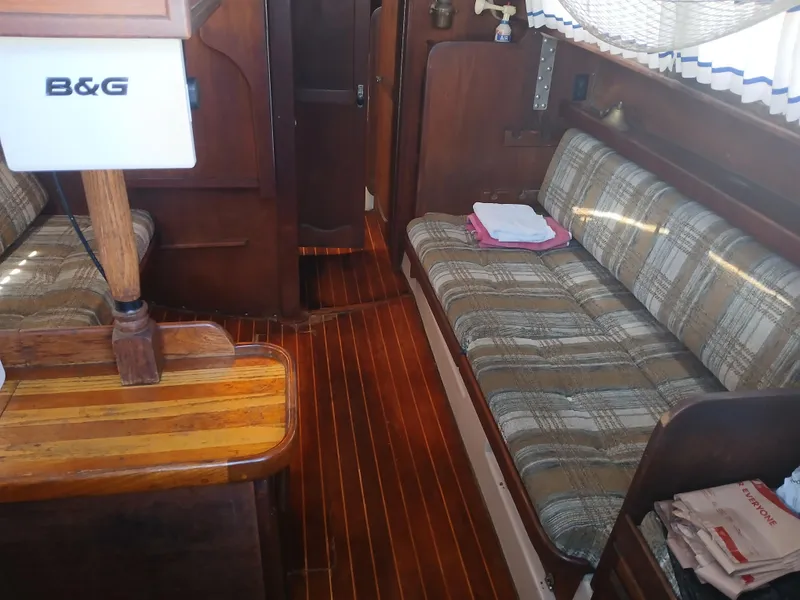 Slide: The Image of Interior of a 1984 Newport Sailboat with plaid seating and wooden flooring. - 12