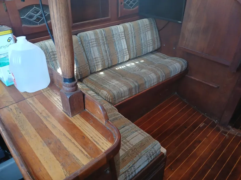 Slide: The Image of 1984 Newport Sailboat interior with wooden flooring and plaid seating. - 19