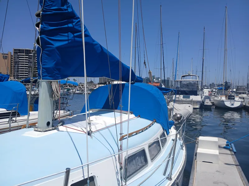 Slide: The Image of 1984 Newport Sailboat docked in marina, blue covers, clear sky, calm water. - 3