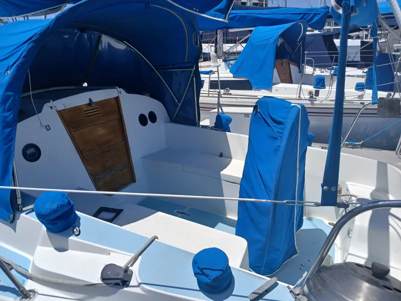 Slide: The Image of 1984 Newport Sailboat cockpit with blue covers and canopy in marina. - 5