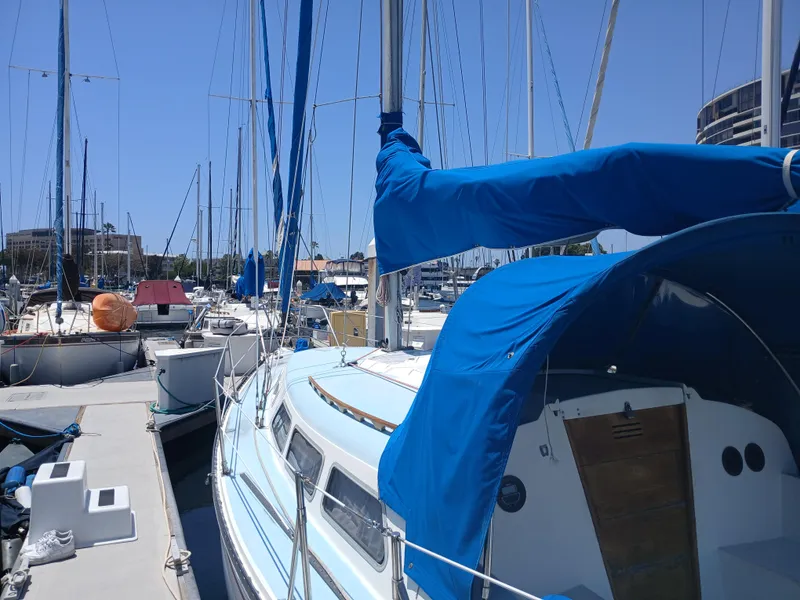 Slide: The Image of 1984 Newport Sailboat docked in marina, blue covers, clear sky, calm waters. - 6