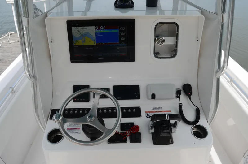 Slide: The Image of 2017 Contender 28 Sport boat dashboard with steering wheel, navigation screen, and controls. - 2