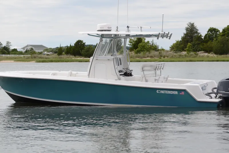 Slide: The Image of 2017 Contender 28 Sport boat on calm water, side view, with trees in the background. - 5