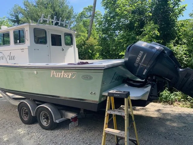 Slide: The Image of 2015 Parker 2530 Extended Cabin boat on trailer with Yamaha outboard motor, parked outdoors. - 2