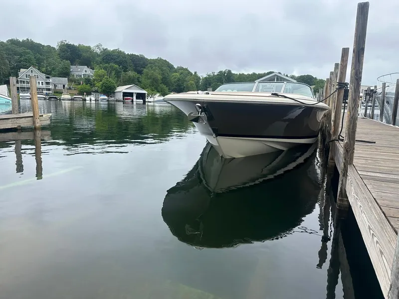 Slide: The Image of 2019 Chris-Craft Launch 30 docked on calm water, surrounded by lush greenery. - 2