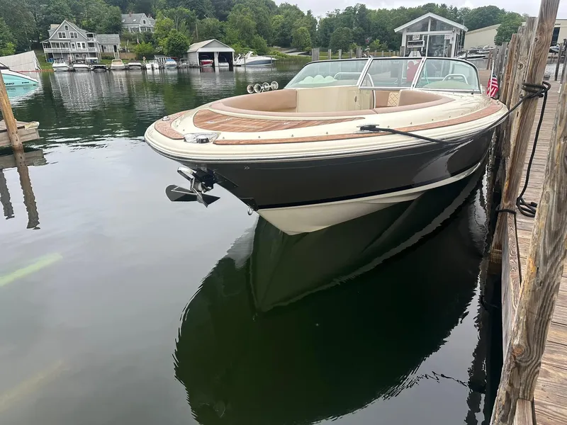 Slide: The Image of 2019 Chris-Craft Launch 30 boat docked on calm water, surrounded by lush greenery. - 3