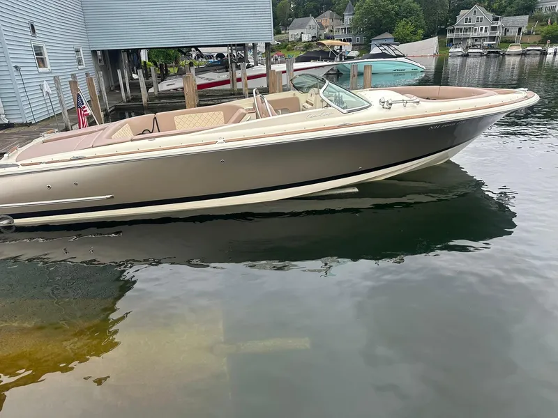 Slide: The Image of 2019 Chris-Craft Launch 30 boat docked on calm water near blue buildings. - 5