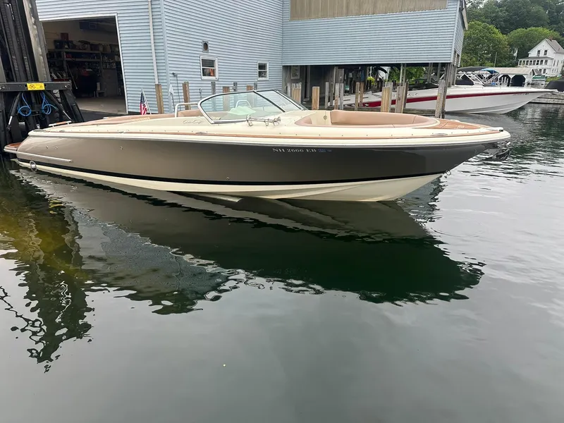 Slide: The Image of 2019 Chris-Craft Launch 30 boat docked at marina, sleek design, calm water reflection. - 6