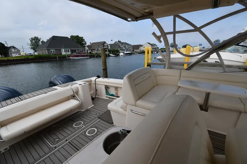Slide: The Image of 2018 Grady-White Freedom 335 boat interior with seating and table, docked by waterfront homes. - 25