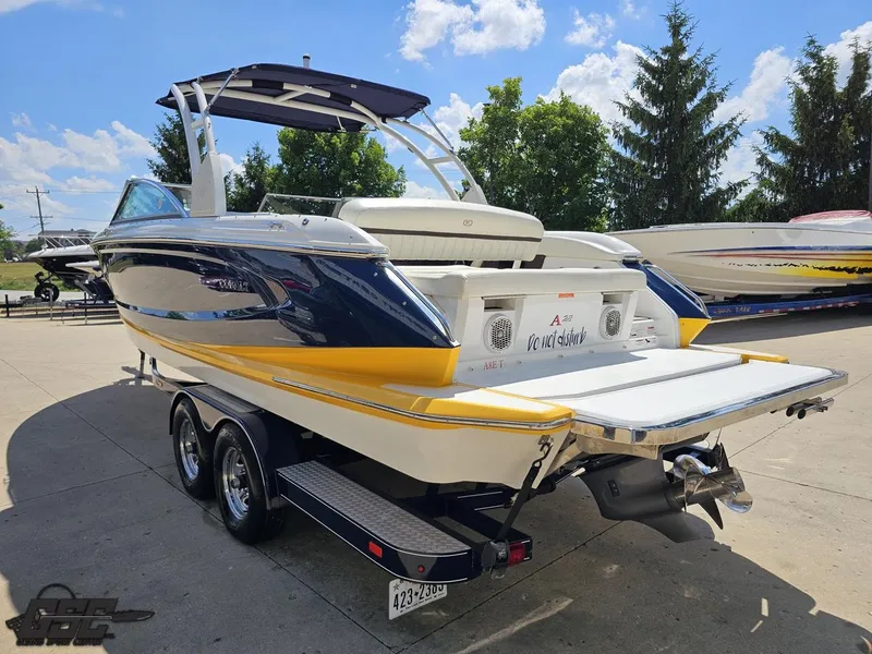 Slide: The Image of 2015 Cobalt A28 boat on trailer, sunny day, blue and yellow design, outdoor setting. - 22