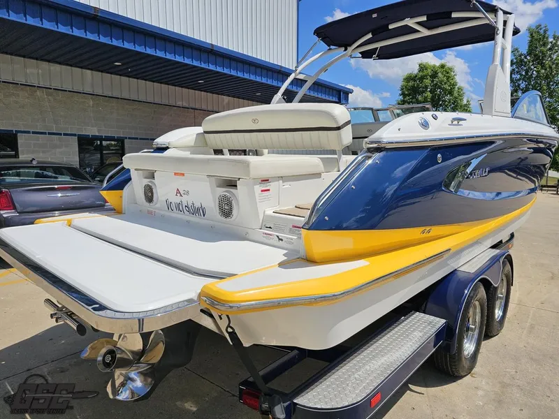 Slide: The Image of 2015 Cobalt A28 boat with blue and yellow accents on a trailer, parked outdoors. - 28