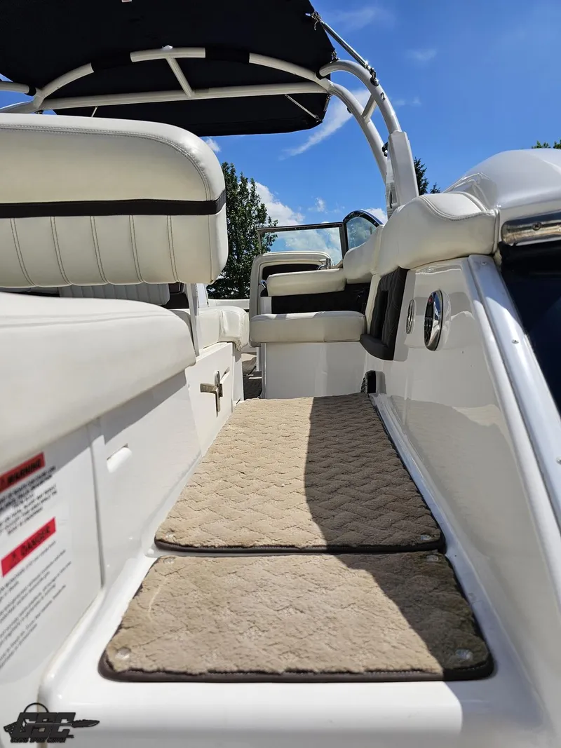Slide: The Image of 2015 Cobalt A28 boat interior with white seating and beige carpet under a blue sky. - 29