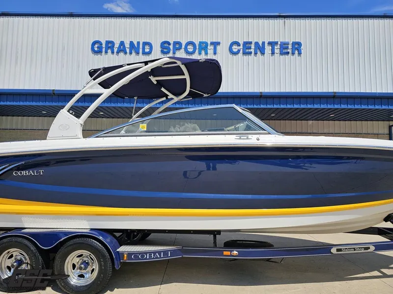 Slide: The Image of 2015 Cobalt A28 boat at Grand Sport Center, blue and yellow design on trailer. - 3