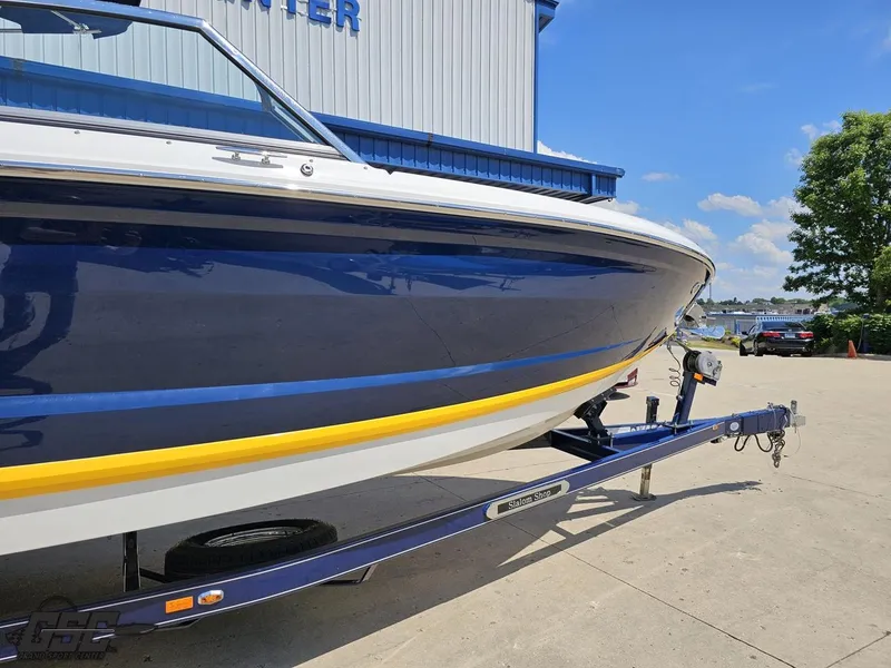 Slide: The Image of 2015 Cobalt A28 boat on trailer, blue and yellow design, parked outdoors. - 4