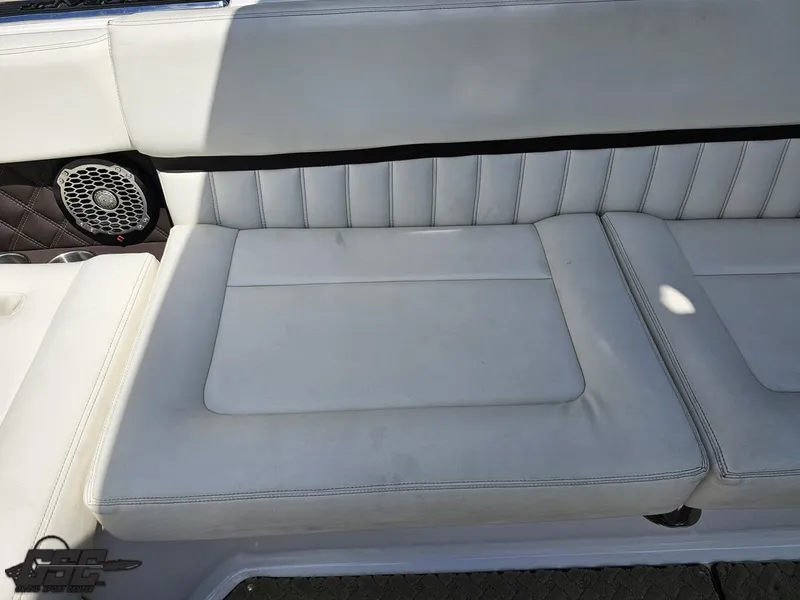 Slide: The Image of White leather seating on a 2015 Cobalt A28 boat, featuring a speaker and cup holders. - 49